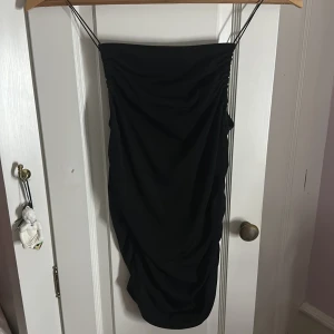 Svart linne/blus med tunna axelband - Säljer en svart kort linne med tunna axelband och snygg rynkdetalj längs sidorna. Linnet är figurnära och har en enkel, stilren look som passar perfekt när du vill känna dig extra snygg. Materialet känns mjukt och följsamt mot kroppen. Säljer för den inte kommer till användning och bara hänger i min gaderob 💗 Super snygg, använt 2 gånger ‼️