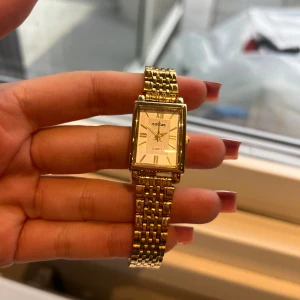 Guldig rektangulär klocka från Sottas - Snygg klocka från Sottas med rektangulärt ur och klassisk länk i guldton. Klockan har romerska siffror på urtavlan och en elegant, tidlös design som passar perfekt till din stil. Batteriet behöver bytas! Stainless steel