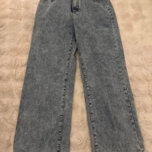 Blå raka jeans från Shein, storlek L - Snygga ljusblå jeans från Shein i storlek L med rak passform och klassisk femficksdesign. Jeansen har hög midja och är tillverkade av bomull och polyester för en skön känsla. Perfekt för dig som gillar en chill och stilren look.