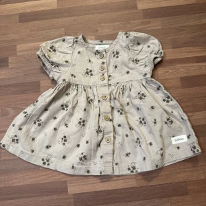 Limited edition klänning - Supersöt limited edition klänning från Newbie i storlek 56 (1-2mån). Träknappar fram. Upptvättad men ej använt. I nyskick. 