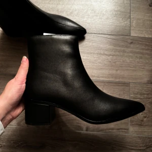 Svarta ankelboots med spetsig tå - Helt oanvända, Snygga svarta stövletter med spetsig tå och låg klack. Dem var tyvärr för stora för mig, säljer då jag glömde returnera inom returperioden. Nypris 550 kr på hemsidan
