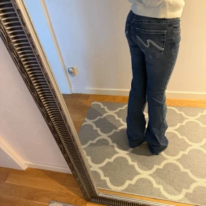 Blå bootcut jeans från Nelly - Snygga blå jeans från Nelly med bootcut passform och vitt på fickorna 