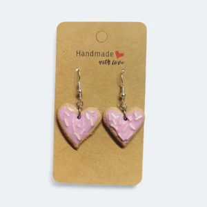 Hjärtan öronhängen - Supergulliga handgjorda örhängen formade som hjärtan med ljusrosa glasyr och vita /rosa strössel. Hängsmyckena har en brun botten som ser ut som små kakor, och krokar i silverfärg. Perfekt för dig som gillar söta och unika accessoarer.