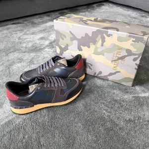 Valentino rockunners  - Snygga Valentino Garavani Rockrunner sneakers i svart och mörkblått med röda detaljer på hälen. Perfekta för dig som vill sticka ut med stilrena och lyxiga sneakers. ✅Kvitto finns✅