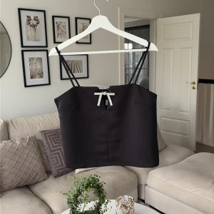 Svart satin korsett-topp med rosett - Säljer denna superfina topp från HM. Den är i nyskick, aldrig använd.