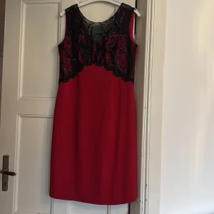 Röd paljettklänning från Escape - Snygg röd kortklänning från Escape med svart mesh och glittriga paljettdetaljer upptill. Klänningen är ärmlös och har en v-ringad rygg samt dragkedja bak. Perfekt för dig som vill sticka ut med en cool och elegant look.