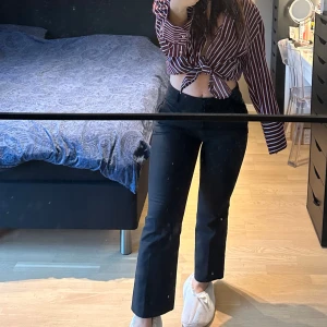 Svarta bootcut kostymbyxor - Snygga svarta kostymbyxor med bootcut passform och hög midja. Byxorna har bälteshällor, två bakfickor och en metallring-detalj vid ena fickan. Materialet är mjukt och har lite stretch, perfekt för en trendig look. Ny pris 699kr.