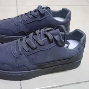 Mörkgrå sneakers med snörning - Snygga mörkgrå sneakers med platt sula och rund tå. Skorna har klassisk snörning och är tillverkade i ett mjukt syntetmaterial som ger en clean och stilren look. Perfekta för dig som gillar minimalistisk stil och vill ha ett par schyssta sneakers till vardags.