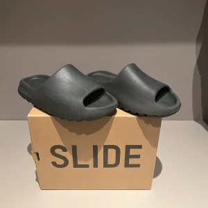Adidas Yeezy Slide mörkgrå - Adidas Yeezy slides i storlek 42 men jag skulle rekommendera dessa för dom som har 41 eftersom dessa är lite små i storlekarna. Skönaste tofflorna du kan hitta. När du har provat ett par så kommer du förstå att de är dom skönaste tofflor då någonsin har tagit på dig. Hör av dig vid frågor eller funderingar i dm🤗