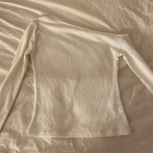Vit ribbad offshoulder tröja Gina Tricot - Säljer en vit ribbad långärmad tröja från Gina Tricot i storlek S. Tröjan har en snygg offshoulder-design. 