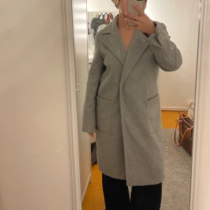 Lång grå kappa - Oanvänd lång kappa som köptes för ca 1-2 år sedan. Fattas ”bältet”, men lika fin utan💕
