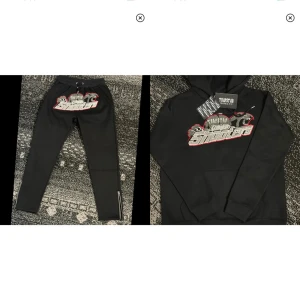 Svart Trapstar tracksuits helt nya med broderi  - Svart tracksuit helt nya från Trapstar med stort broderat 'Shooters' motiv i grått, vitt och rött på bröstet. Klassisk huva med snörning och ribbade muddar. Perfekt streetwear-vibe och riktigt snygg detalj med broderiet framtill.