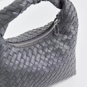 Grå flätad axelväska med dragkedja - Snygg grå axelväska med flätad design och praktisk dragkedja. Väskan har en mjuk, rundad form och är tillverkad i skinn. Perfekt för dig som gillar stilrena detaljer och vill ha en unik accessoar.