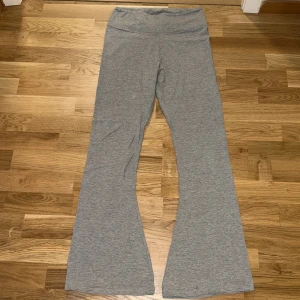 Grå bootcut mjukisbyxor - Använt 3 gånger Säljer ett par grå mjukisbyxor med bootcut-ben och hög midja. Byxorna är tillverkade i mjukt bomullsmaterial med stretch och har en enkel, clean look utan synliga detaljer eller fickor. Perfekta för chill dagar eller när du vill vara bekväm.