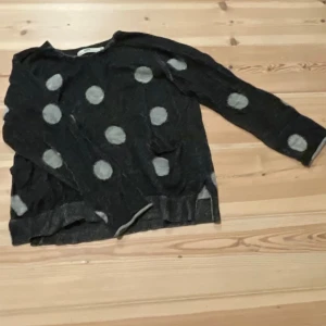 Svart stickad tröja med prickar från Hope - Cool svart stickad tröja från Hope med stora vita prickar över hela plagget. Tröjan har rund halsringning och långa ärmar. Perfekt för dig som gillar unika mönster och ha cozy kläder!!🥰