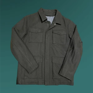 Mörkgrön overshirt från Selected Homme - Snygg mörkgrön overshirt från Selected Homme i ullmix. Jackan har fyra stora fickor framtill, klassisk krage och stängs med dragkedja och tryckknappar. Perfekt för lager-på-lager och har en clean, stilren look som funkar till många outfits.
