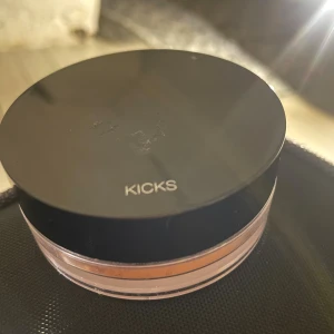 KICKS Glam Bronze mineralpuder - Snyggt mineralpuder från KICKS i nyansen Glam Bronze. Kommer i en rund transparent burk med svart lock. Ger en bronzig glow till ansiktet och innehåller naturliga ingredienser som mica och solrosolja. Perfekt för att skapa en solkysst look.