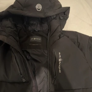 Sail Racing Vinterjacka - Säljer en svart vinterjacka från Sail Racing  i mycket bra skick. Använd mycket sparsamt endast i 4 månader. Finns ett få defekter på jackan som gör så att jag kan sänka priset lite! Bara att höra av till mig vid fler specifika bilder! PRIS KAN DISKUTERAS VID SNABB AFFÄR!!!!!!