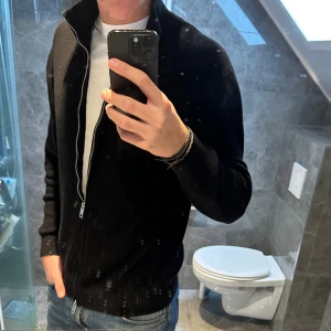 Svart stickad kofta med dragkedja - Svart stickad kofta från H&M passar perfekt nu till höst och vinter. Tröjan är i riktigt bra skick och har inga defekter. Jag på bilden är 188cm. Hör av er vid frågor:) 