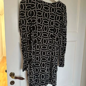 Svartvit prickig klänning H&M - Svart kortklänning från H&M med vitt prickigt mönster i coolt grafiskt mönster. Långärmad modell med rund hals och figurnära passform. Perfekt för dig som gillar att sticka ut med mönster. Materialet känns mjukt och följsamt.