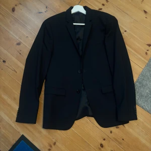 Marinblå  klassisk kavaj - Stilren marinblå kavaj med två knappar framtill och klassiska fickor. Perfekt för dig som vill ha en tidlös och snygg look. Fodrad insida och enkel passform som funkar till skjorta eller t-shirt.