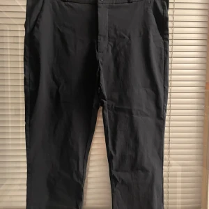 Svarta kostymbyxor från Freequent XXL - Snygga svarta kostymbyxor från Freequent i storlek XXL. Klassisk rak passform med diskreta fickor fram och bak, samt hällor för bälte. Materialet är mjukt och har en lätt stretch för extra komfort. Perfekt för dig som gillar stilrena och enkla byxor.