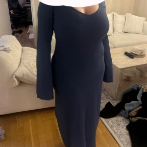 NA-KD kläning - Snygg marinblå långklänning med ribbad struktur och v-ringad hals. Klänningen har långa ärmar och en figurnära passform som framhäver siluetten. Perfekt för dig som gillar stilrena och enkla plagg med en modern touch.