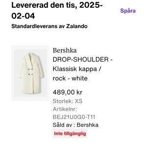 Vit kappa från Bershka XS - Snygg vit kappa från Bershka med klassisk dubbelknäppning och breda slag. Jackan har två framfickor med lock och svarta knappar som kontrast. Materialet är mjukt och har en ullig känsla, perfekt för kyliga dagar.