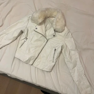 Vit skinnjacka  - En vit skinnjacka med vit fakepäls. Pälsen är lite missfärgad men det går att ta av den. Köparen står för frakt 
