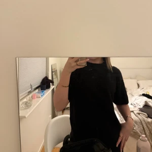 Svart stickad tröja med kort ärm - En svart stickad tröja med rund hals och korta ärmar. Modellen är loose fit och har en enkel, stilren design som är lätt att matcha. Perfekt för dig som gillar en chill och avslappnad look.