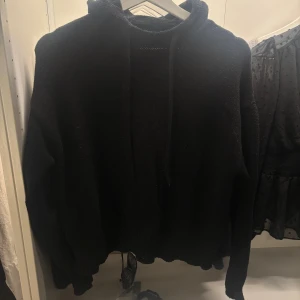 Svart stickad hoodie från Zara - Mysig svart stickad hoodie från Zara i storlek S. Tröjan har huva med snörning och långa ärmar. Perfekt för kyliga dagar och enkel att matcha med jeans eller leggings. Tjockt och mjukt material som känns skönt mot huden. Finns lite täcken på användning.