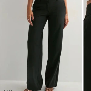 Svarta wide kostymbyxor - Snygga svarta kostymbyxor med wide fit och hög midja. Byxorna har raka ben, bälteshällor och diskreta bakfickor. Perfekta för en clean och stilren look. Materialet känns mjukt och har en lätt stretch för extra komfort.
