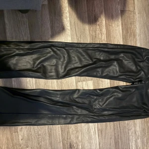 Svarta skinnbyxor med rak passform - Snygga svarta skinnbyxor med rak siluett och klassisk design. Byxorna har en slät yta och sitter bekvämt med normal passning. Perfekta för dig som vill ha en cool och stilren look med edge. Från Bikbok storlek 34