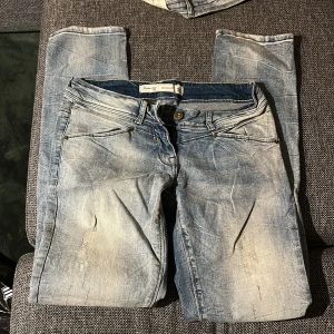 Lågmidjade jeans - Snygga Lågmidjade jeans från Jeanswear 72D med regular passform. De har en klassisk design, ljus tvätt med slitningar och kontrastsömmar. Modellen är rak och har knapp och dragkedja framtill samt detaljerade bakfickor med broderi. Midjan är W28 och passar mig som är 170