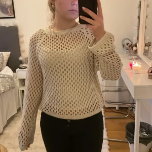 Beige stickad tröja från Bik Bok - Säljer en beige stickad tröja från Bik Bok i storlek S. Tröjan har ett hålmönster över hela och ribbade muddar vid hals, ärmslut och nederkant. Perfekt för lager-på-lager.
