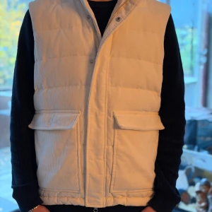 Vit stenströms väst - Snygg vit dunväst från stenströms i manchester. Västen har quiltad design, två stora fickor framtill och stängs med dragkedja och tryckknappar. Perfekt för lager-på-lager och ger en clean look till din outfit. Det är storlek M på den har inte använt den alls mycket så den är som ny. Skortar ungefär 4000 ny pris 