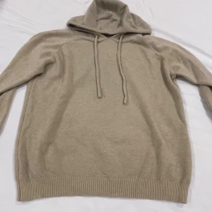 Beige hoodie med huva och snörning - Snygg beige hoodie med huva och snörning framtill. Tröjan har långa ärmar och ribbade muddar vid ärmslut och nederkant. Perfekt för dig som gillar en enkel och stilren look. Materialet känns mjukt och skönt mot huden.