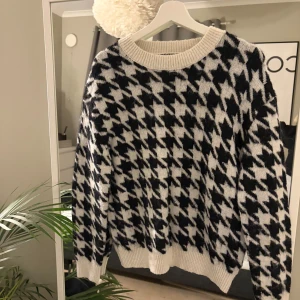 Svartvit stickad tröja med mönster - Säljer en stickad tröja i svart och vitt med  mönster. Tröjan har rund hals, ribbade muddar och är långärmad. Lite oversized.