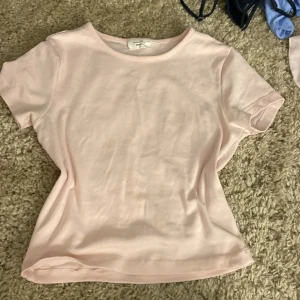 Ljusrosa t-shirt från Gina Tricot - Säljer en ljusrosa t-shirt från Gina tricot. Modellen har rund halsringning och korta ärmar. Mjuk och skön bomullskvalitet.