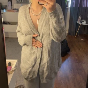 Grå kofta från H&M L.O.G.G. XS - Mysig och oversized grå kofta från H&M L.O.G.G. i storlek XS. Koftan har lång ärm, ribbade muddar och bred ribbad kant framtill. Perfekt att slänga på sig när det är lite kyligt. Materialet är mjukt och stickat för extra comfort.