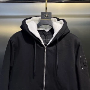 Svart hoodie från Moose Knuckles - Svart hoodie från Moose Knuckles med vit fluffig fuskpäls i huvan och quiltad insida. Tröjan har dragkedja framtill, snörning vid huvan och en snygg logodetalj på ärmen. Perfekt för kalla dagar och har en riktigt clean look. Aldrig använts för, Liten i storlek passar även 176!