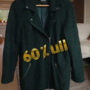 Mörkgrön ulljacka från Monki i stl S/M - Snygg mörkgrön/svart rock/jacka från Monki med 60% ull. Jackan har coola detaljer som snedställd dragkedja, två zip-fickor och klassisk krage med tryckknappar. Perfekt för dig som vill ha en stilren och varm jacka med lite edge.