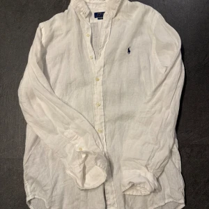 Polo Ralph lauren linneskjorta - Snygg vit linneskjorta till sommaren från Polo Ralph lauren i classic fit modell. Storleken är M och säljer för att den är för stor. Använd endast en gång, inga defekter eller liknande. Nypris är 2295kr.