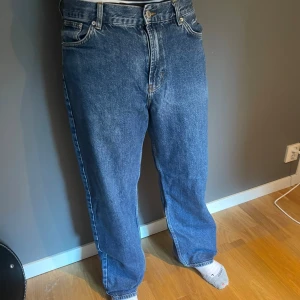 Blå baggy jeans - Säljer ett par blå baggy jeans med klassisk femficksdesign och ljus tvätt. Jeansen har hög midja, raka ben och tydliga sömmar. Materialet är robust denim och passformen är loose för en chill vibe.