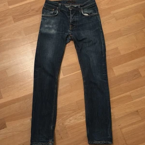 Mörkblå jeans från Nudie Jeans - Snygga jeans från Nudie. Storlek: 29/30. Modell: Grim Tim. Skick: 8/10. Finns en liten defekt (bild 3). Skriv om ni har funderingar!