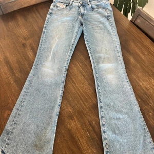 Bootcut jeans från Diesel Industry - Snygga ljusblå bootcut jeans från Diesel Industry med klassisk femficksdesign och tydliga Diesel-loggor på både ficka och bakre läderpatch. Jeansen har en lätt tvättad look och är tillverkade i slitstarkt bomullsdenim. Perfekt för dig som gillar retrovibbar och bredare benslut.