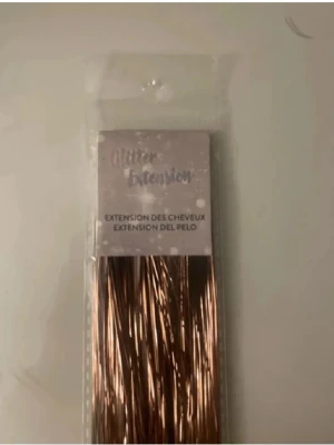 Brunt Hår Glitter/Hair Tensils  - Oanvänd och oöppnad. Bruna/Guld glittriga hår extensions som är enkle att använda, instruktioner finns även på baksidan. Perfekt om man vill piffa till sig hår inför tex  fest!