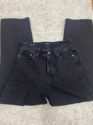 Svarta baggy jeans Jack & Jones - Säljer ett par svarta baggy jeans från Jack & Jones, modell Baggy Alex. Jeansen har fyra fickor, raka ben och klassisk knappgylf. Tillverkade i kraftig bomullsdenim som ger en avslappnad och trendig look.