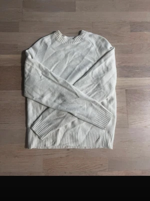 Ljusbeige stickad tröja - En enkel och stilren ljusbeige stickad tröja med rund halsringning och ribbade muddar vid ärmslut och nederkant. Tröjan har en rak passform och är perfekt för lager-på-lager. Materialet ser mjukt och bekvämt ut, perfekt för kyligare dagar.