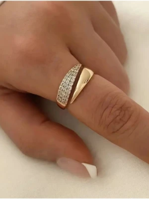 Guldfärgad öppen ring med stenar - Trendig guldfärgad öppen ring med en sida täckt av gnistrande små stenar och den andra sidan slät och blank. Ringen har en modern, asymmetrisk design och är tillverkad i metall med glittrande detaljer. Perfekt accessoar för att lyfta din stil.